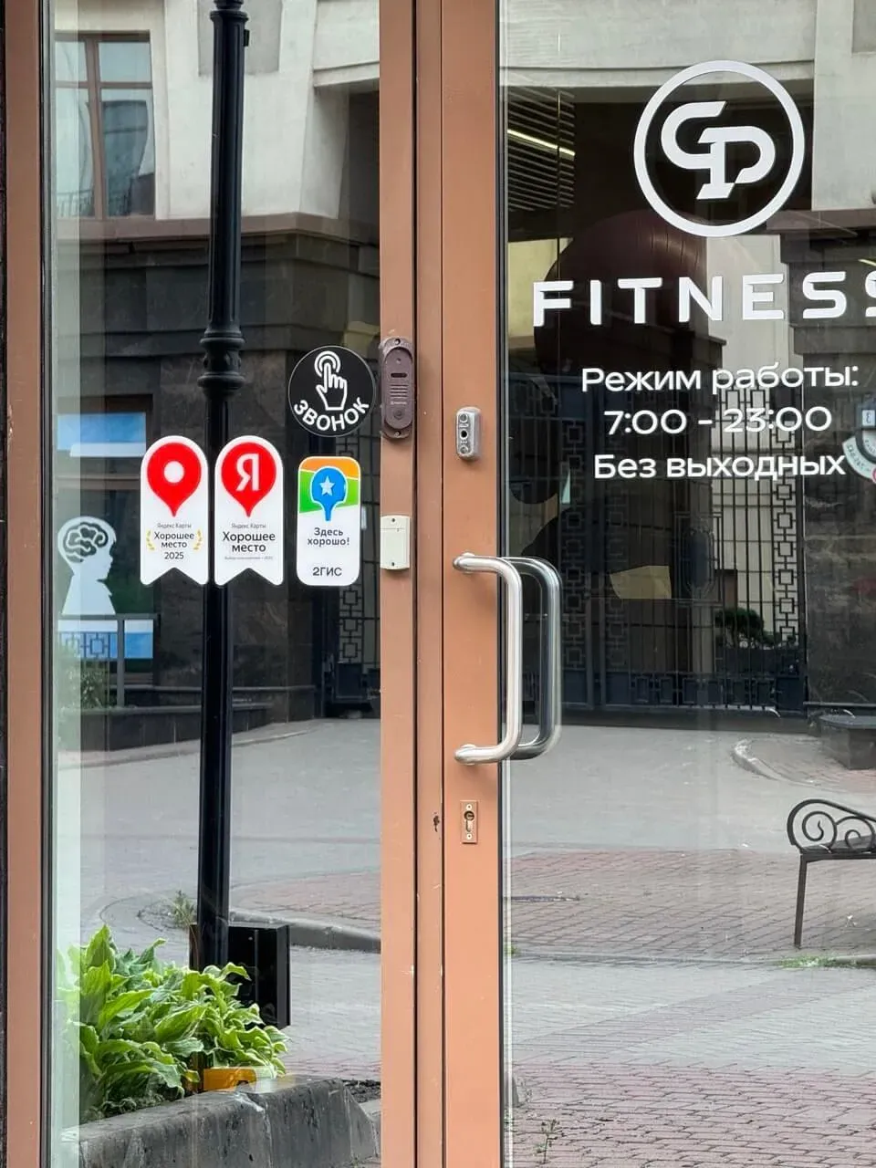 Вход в GP Fitness: режим работы 7:00–23:00 и наклейки с отзывами «Хорошее место»