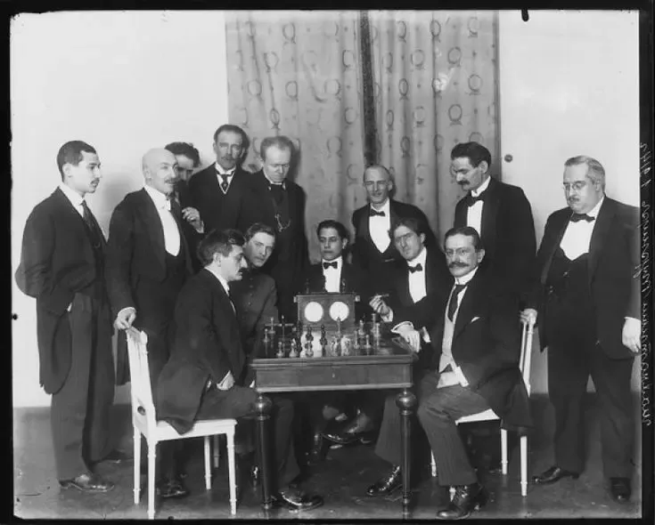 Эмануил Ласкер за партией с Зигбертом Таррашем. За столом наблюдатели: Александр Алехин, Хосе Рауль Капабланка и Фрэнк Маршалл.
