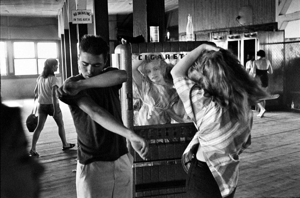 Photographer Bruce Davidson, Brooklyn Gang series. Girl combing hair in the mirror at Coney Island bath house, 1959