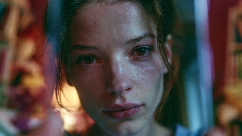Психоанализ селфи: девушка смотрит на своё отражение в экране смартфона