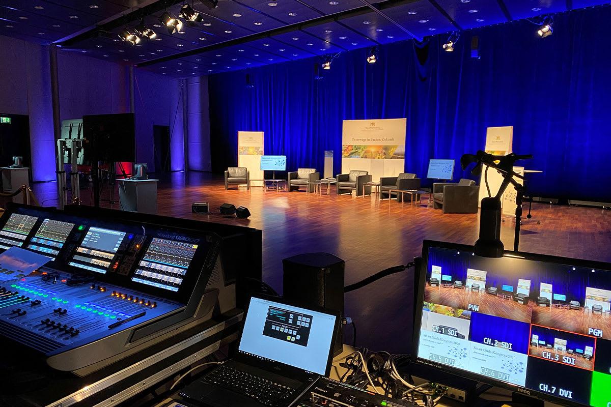 Служба технического контроля контролирует гибридную конференц-сцену с трансляцией с нескольких камер и микшированием звука