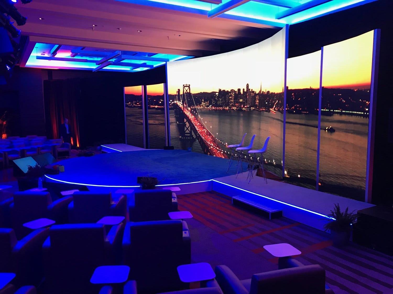 Современная сцена для проведения мероприятий с изогнутым светодиодным экраном, показывающим закат на городском мосту