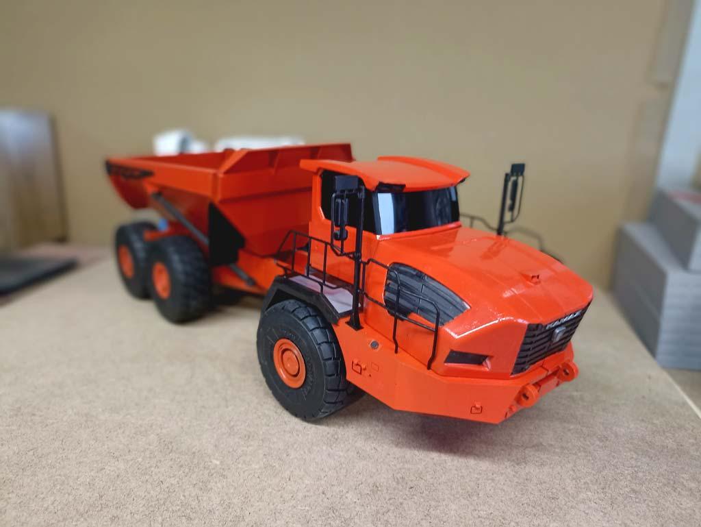 Детально проработанная масштабная модель карьерного самосвала КАМАЗ-6561 «Геркулес» грузоподъёмностью 40 тонн. Модель выполнена в насыщенном оранжевом цвете, подчёркивающем индустриальный характер техники. отчётливо видны элементы шарнирно-сочленённой рамы, массивные колёса размером 29,5 R25, кабина с боковыми зеркалами и самосвальная платформа. Проработаны детали передней решётки с логотипом «КАМАЗ», защитные поручни и элементы ходовой части. Модель демонстрирует особенности конструкции последовательного гибрида: сочетание дизельного двигателя (500 л. с.) и электродвигателя (525 кВт). Подходит для коллекционирования, оформления тематических выставок, посвящённых строительной и карьерной технике, а также для использования в презентационных материалах производителей спецтехники.