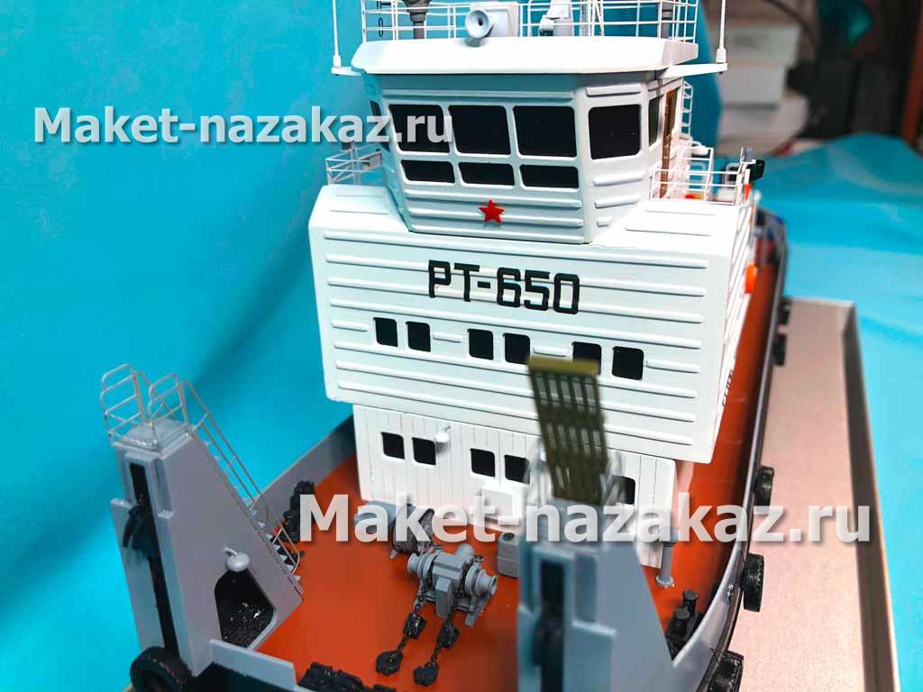 На фотографии представлен макет оранжевого полуприцепа с 12 колесами, выполненный с высокой детализацией. Полуприцеп имеет аккуратные линии и реалистичную отделку, что подчеркивает его предназначение для выставки. Фон изображения ненавязчивый, что позволяет сосредоточиться на модели техники.