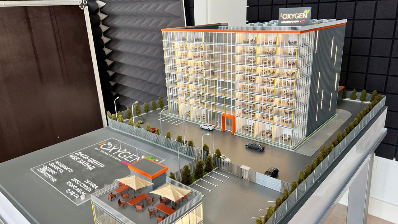 3D-масштабный макет современного дата-центра: многоэтажное здание с прозрачными фасадами, демонстрирующее внутреннюю планировку с рабочими местами. Включены детализированные элементы территории — парковка на 2500 мест, зелёные насаждения, зоны отдыха с мебелью под навесами. Указаны ключевые параметры: мощность 25 МВА, площадь здания 10 000 кв. м, площадь территории 0,78 га. Реалистичная модель для презентации архитектурного и инфраструктурного решения дата-центра.