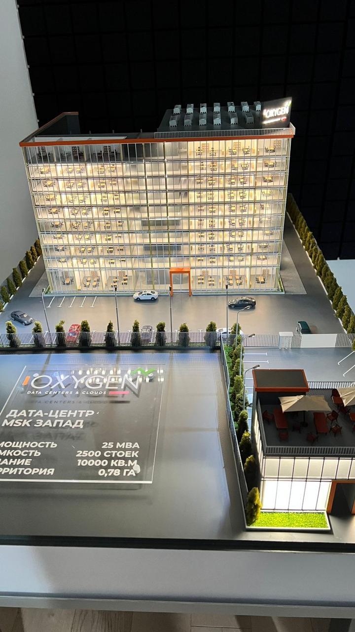 3D-масштабный макет современного дата-центра: многоэтажное здание с прозрачными фасадами, демонстрирующее внутреннюю планировку с рабочими местами. Включены детализированные элементы территории — парковка на 2500 мест, зелёные насаждения, зоны отдыха с мебелью под навесами. Указаны ключевые параметры: мощность 25 МВА, площадь здания 10 000 кв. м, площадь территории 0,78 га. Реалистичная модель для презентации архитектурного и инфраструктурного решения дата-центра.