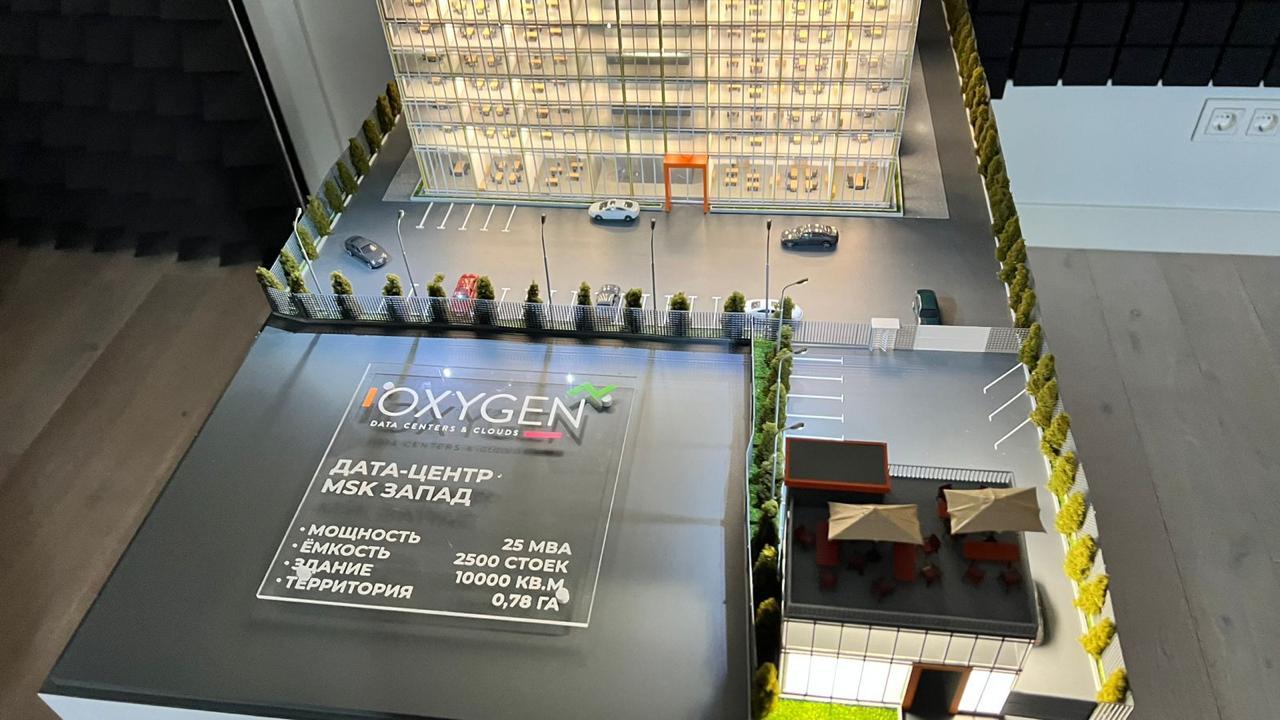 3D-масштабный макет современного дата-центра: многоэтажное здание с прозрачными фасадами, демонстрирующее внутреннюю планировку с рабочими местами. Включены детализированные элементы территории — парковка на 2500 мест, зелёные насаждения, зоны отдыха с мебелью под навесами. Указаны ключевые параметры: мощность 25 МВА, площадь здания 10 000 кв. м, площадь территории 0,78 га. Реалистичная модель для презентации архитектурного и инфраструктурного решения дата-центра.