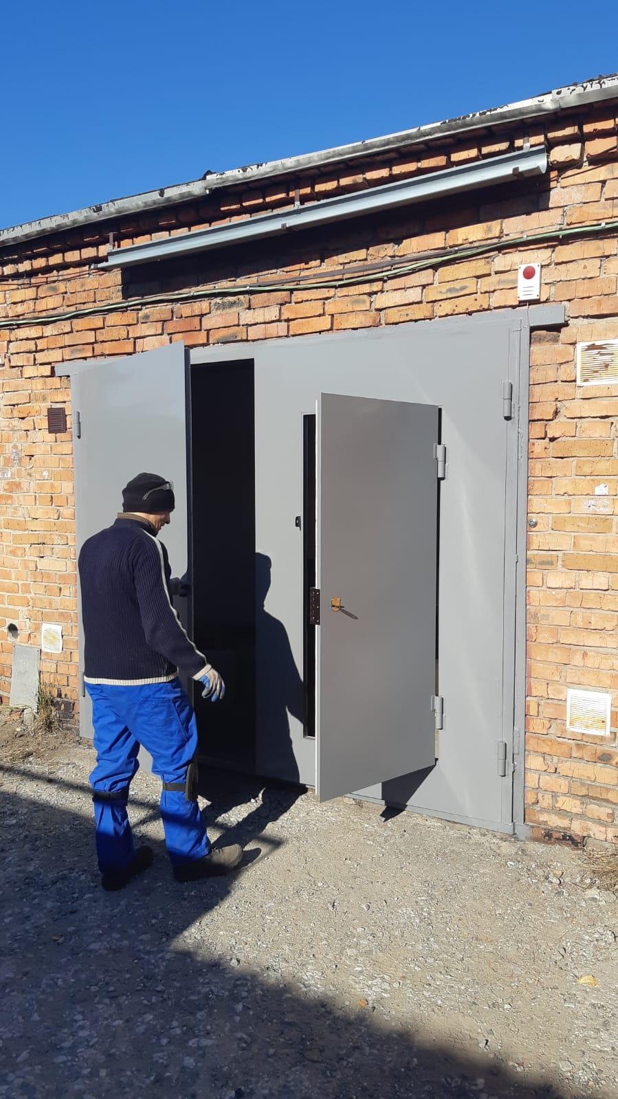 работник Евгений у серых гаражных железных ворот title image alt