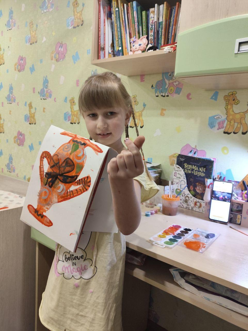 Девочка показывает нарисованную картину с вазой, созданную на занятии по АртДети