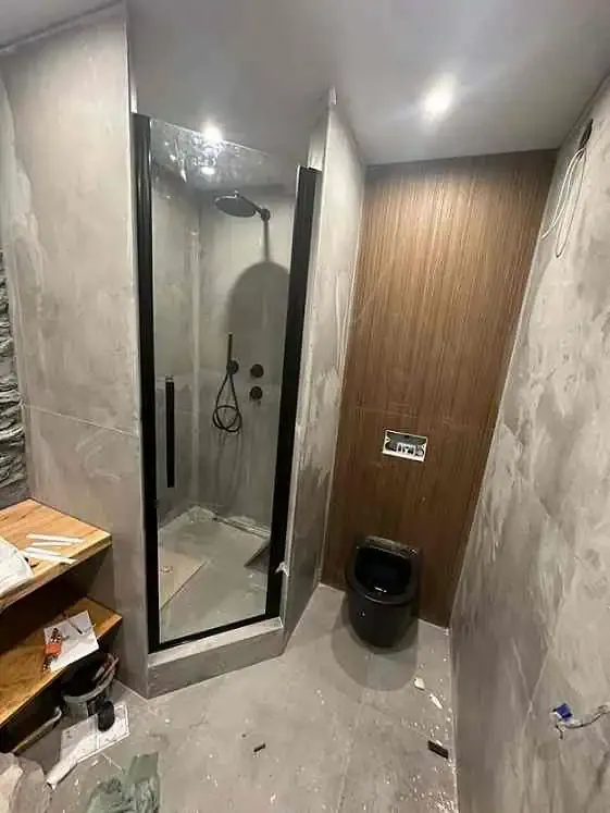 Дверь в душевой кабине с черным профилем — надежная и стильная конструкция, подходит для ванных комнат с деревянными панелями