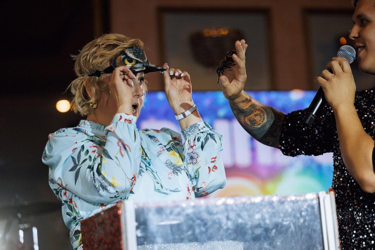 Шоу с животными AMStudio в Москве — ведущий проводит интерактив с гостьей, показывая безопасного паука на праздничной программе