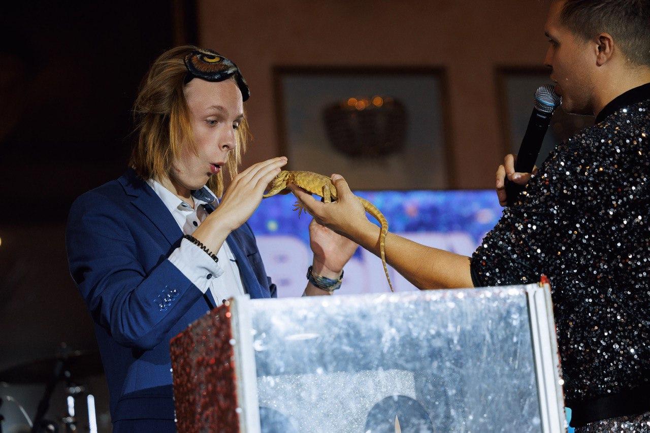 Шоу с животными AMStudio в Москве — ведущий демонстрирует ящерицу, а гость с интересом участвует в интерактиве