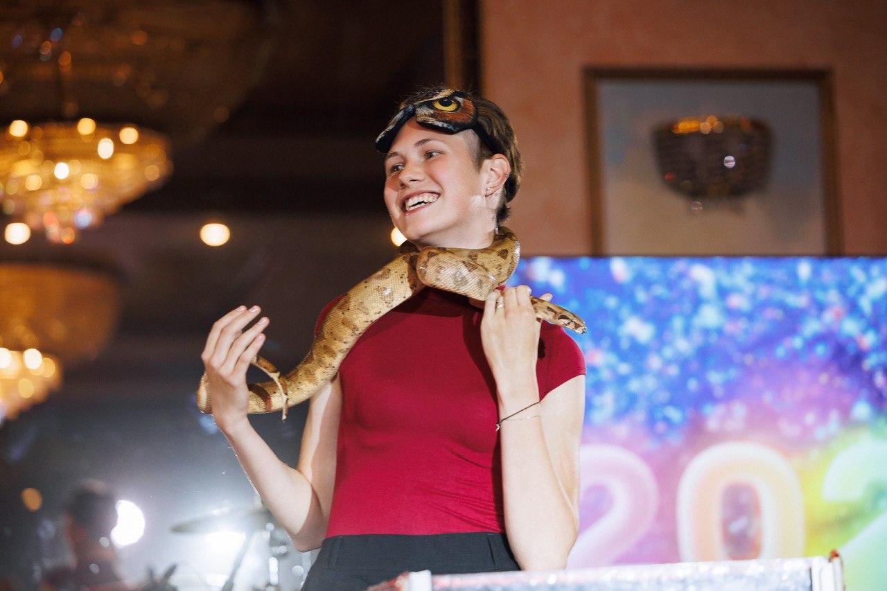 Интерактивное шоу Треш-коробка от AMStudio в Москве — гость с улыбкой держит большую змею на плечах во время праздничной программы